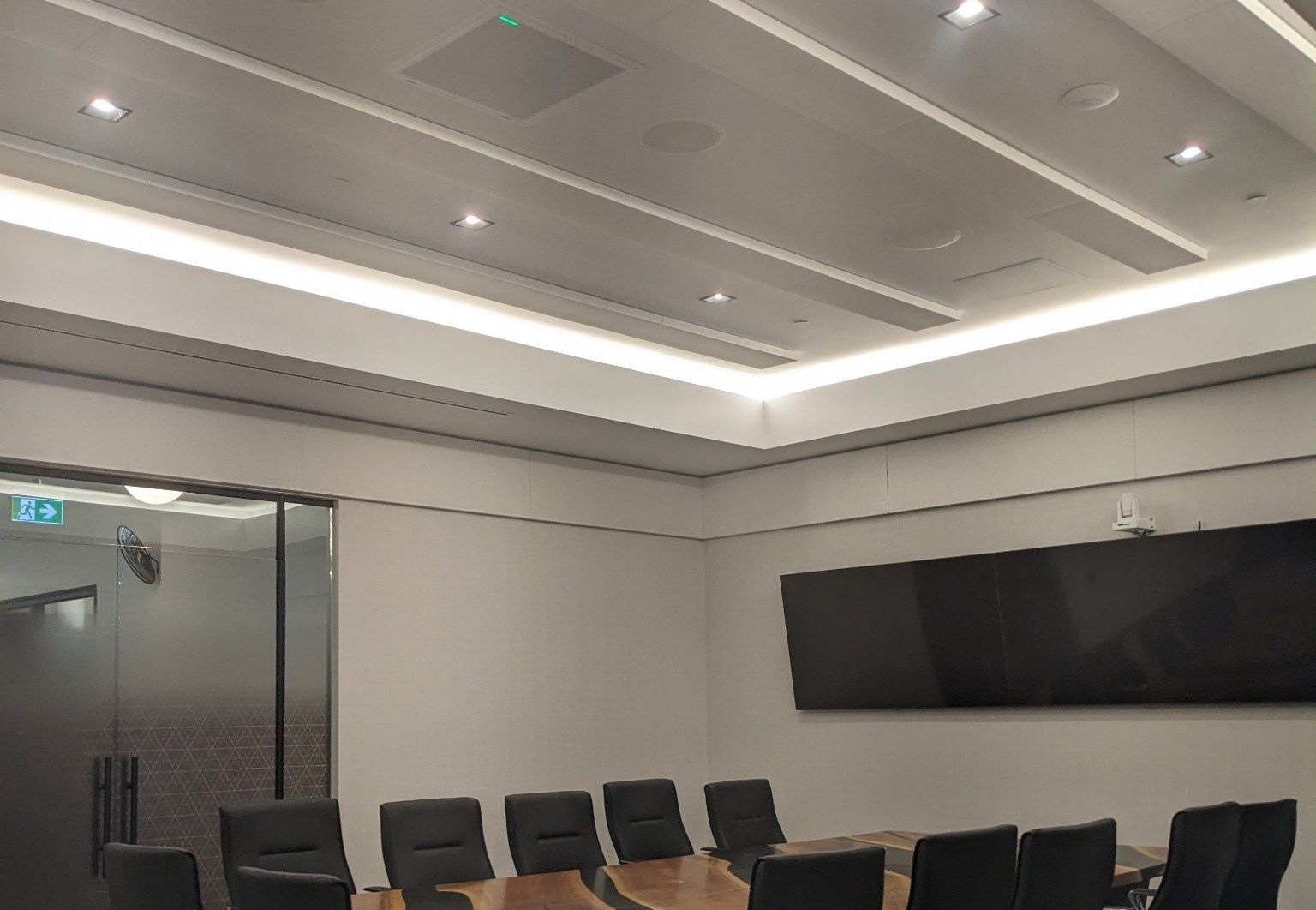 A conference room with a long table and chairs and a flat screen tv.