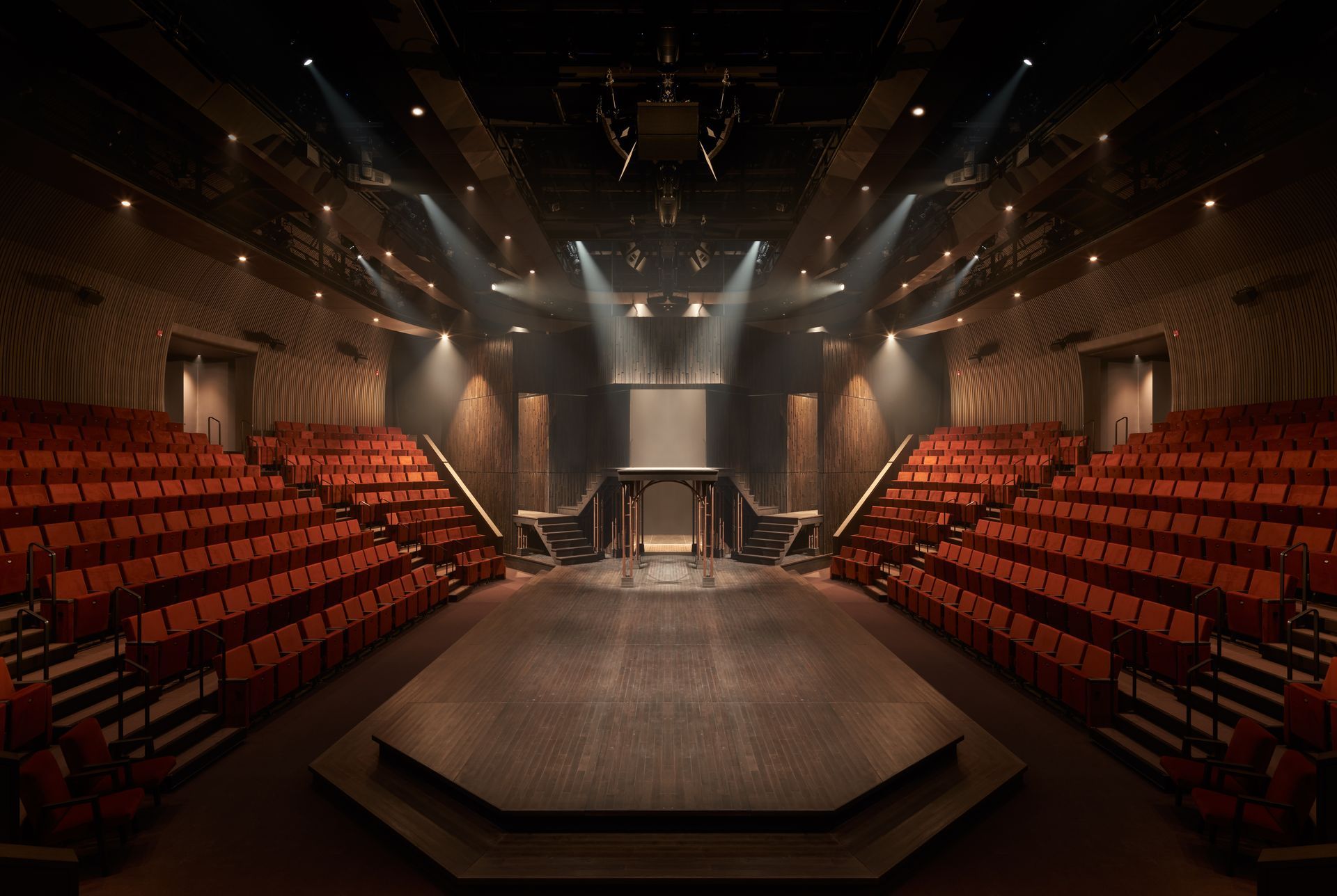 An empty theatre with red seats and a stage.