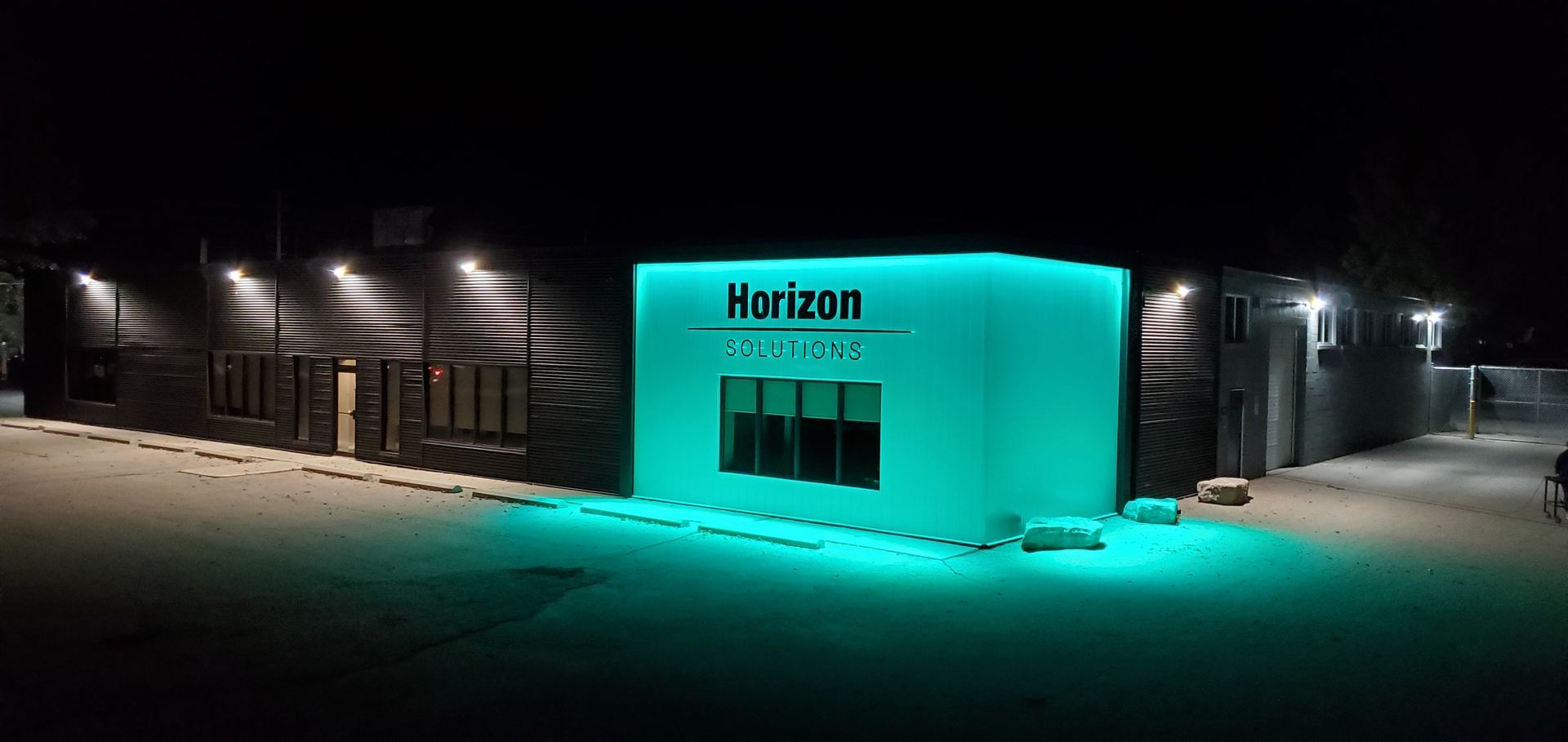 Horizon Solutions office building lit up in teal at night.