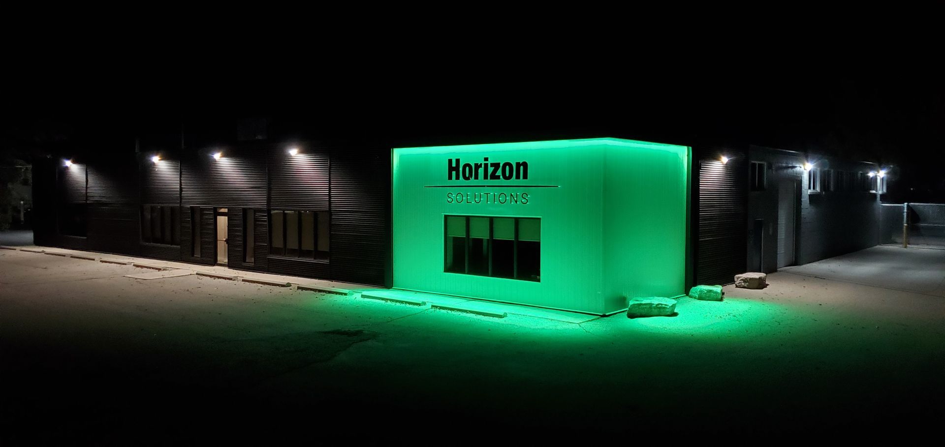 Horizon Solutions office building lit up in green at night.