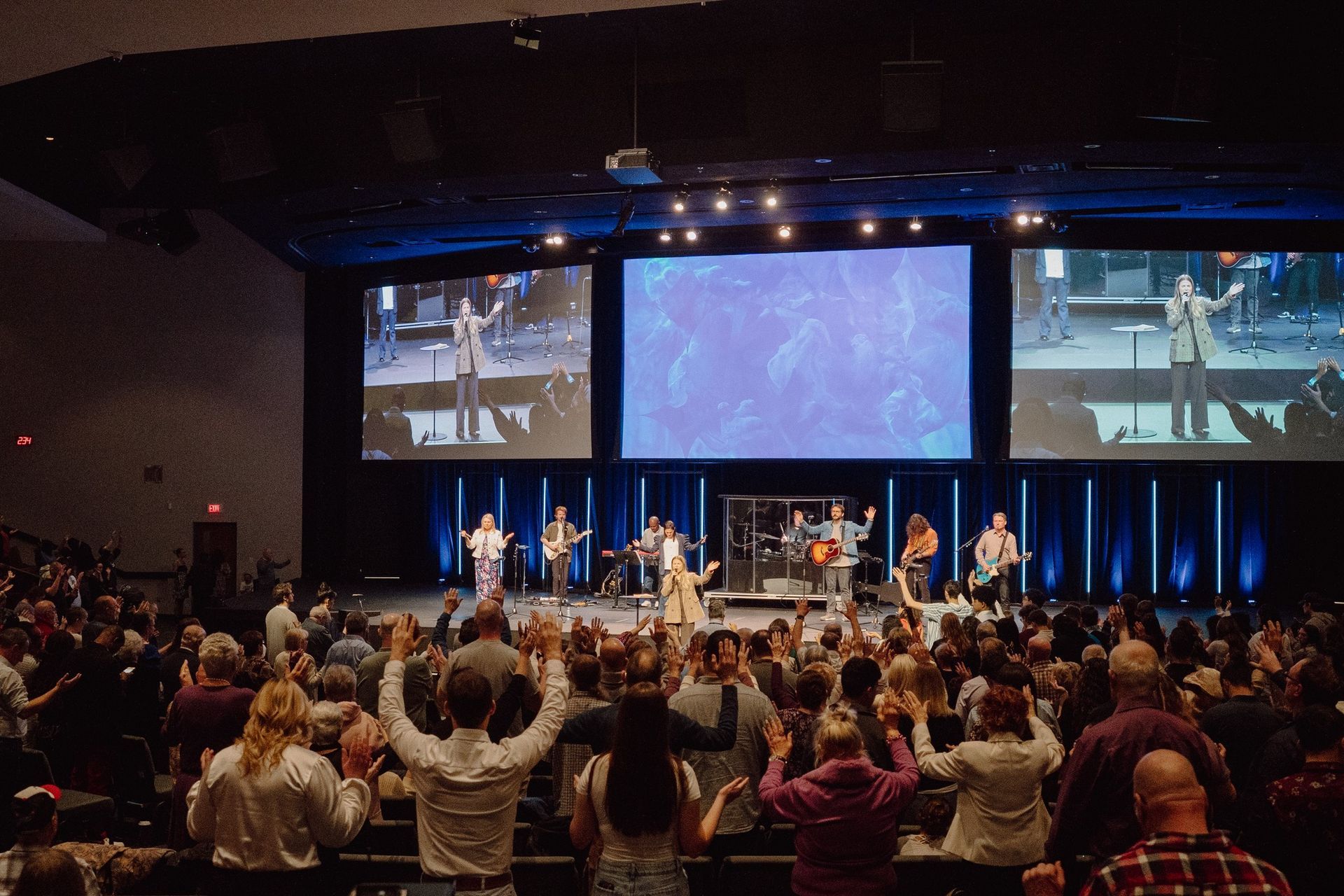 A large crowd of people are watching a concert in a large auditorium.