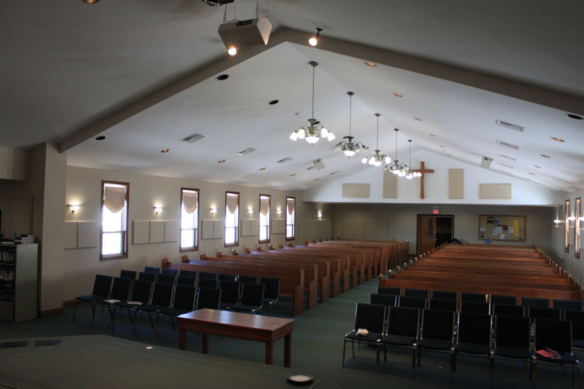 A church with rows of wooden pews and a cross on the ceiling