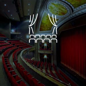 A large auditorium with red seats and a logo on the wall.