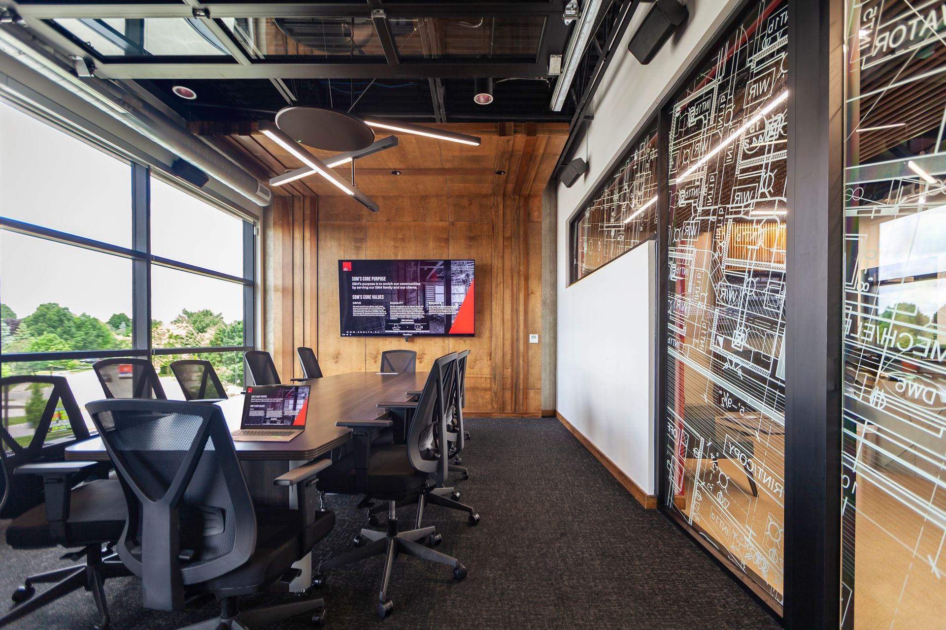 A conference room with a long table and chairs and a large screen on the wall.