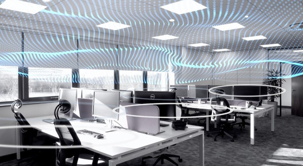 An office with a lot of desks and chairs and a ceiling that looks like a wave.