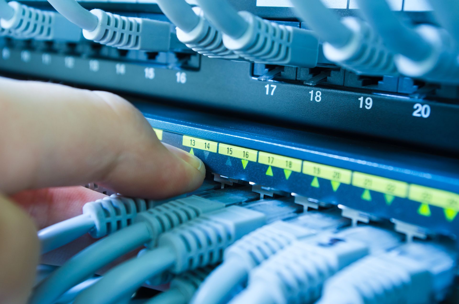 A person is plugging a cable into a network switch.