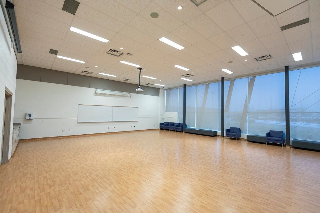 A large empty room with hardwood floors and lots of windows.