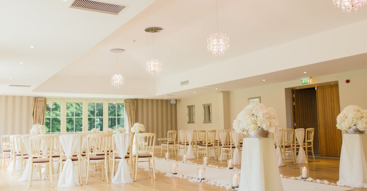 A large room filled with chairs and flowers for a wedding ceremony.