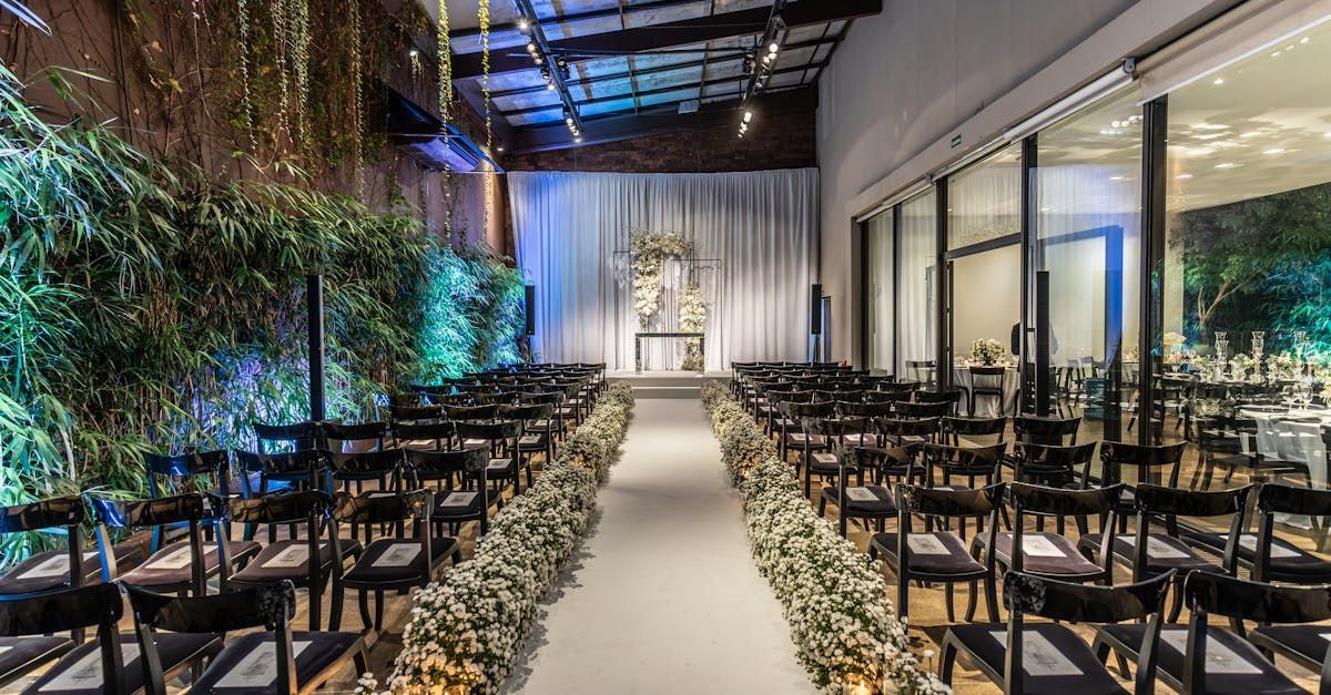 A long aisle with chairs and flowers leading to a stage in a room.
