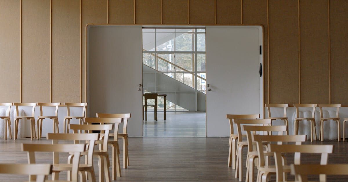 A row of tables and chairs in a room with a staircase in the background