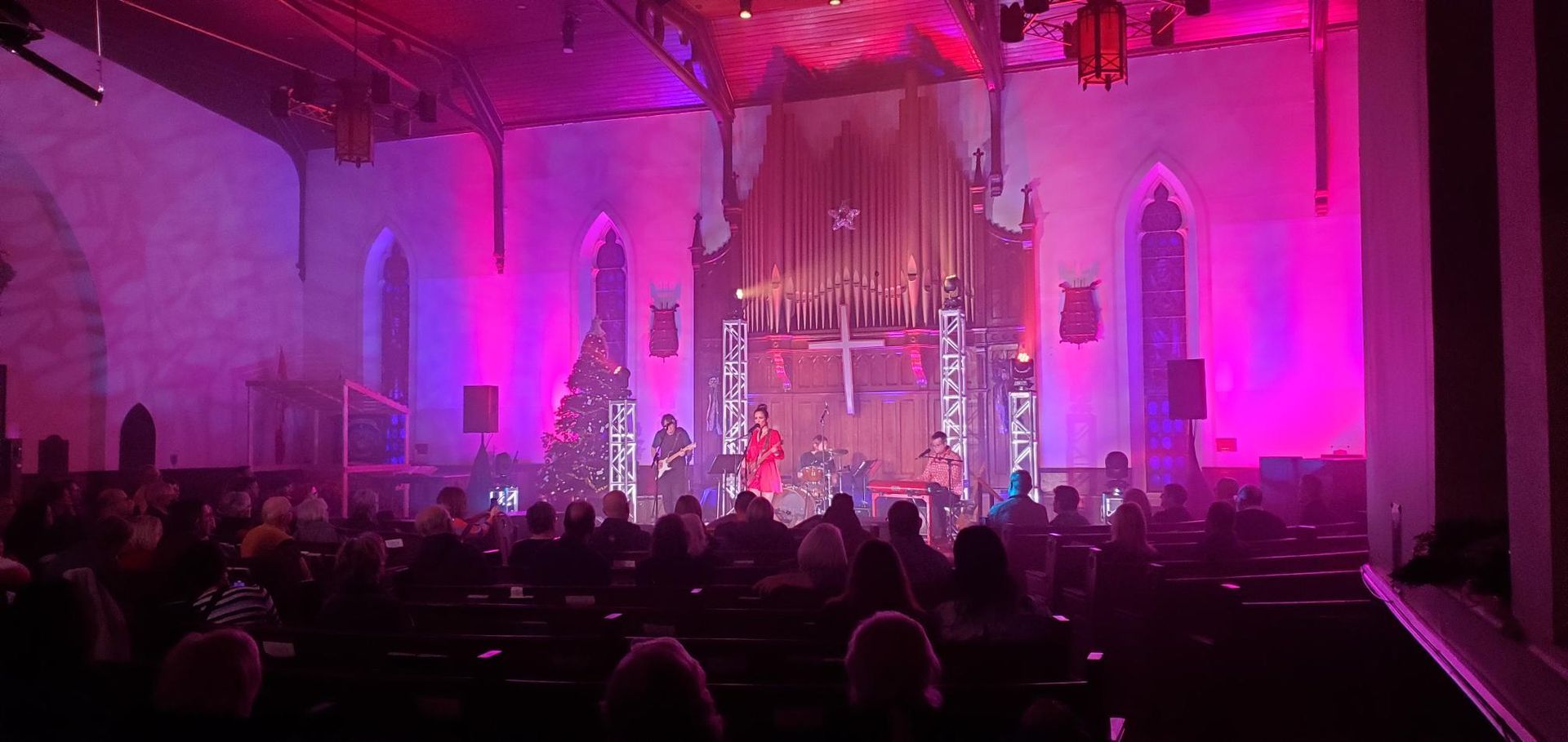 A crowd of people are sitting in a church watching a concert.