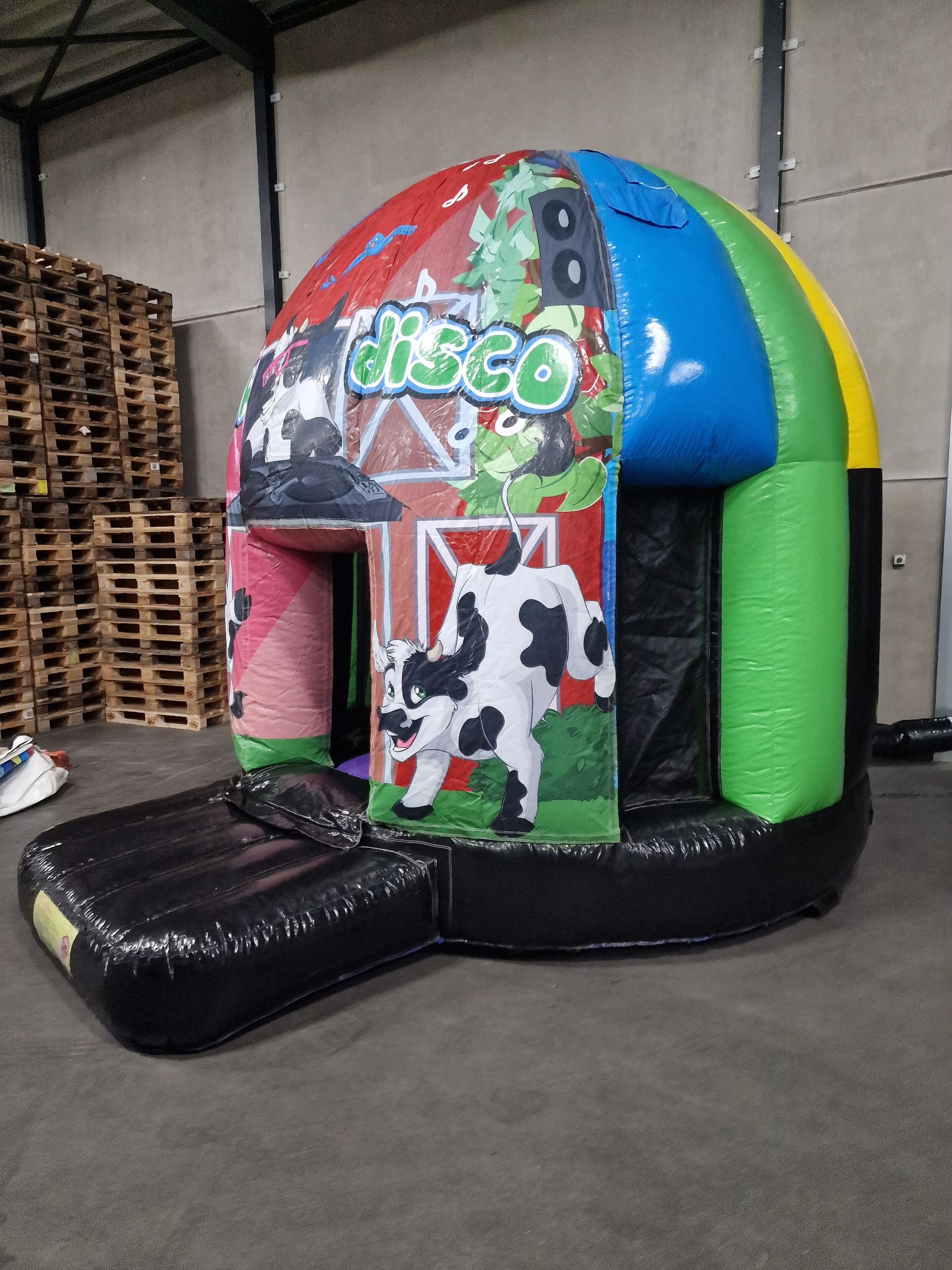 Een kleurrijk springkussen met koeien en het woord disco erop