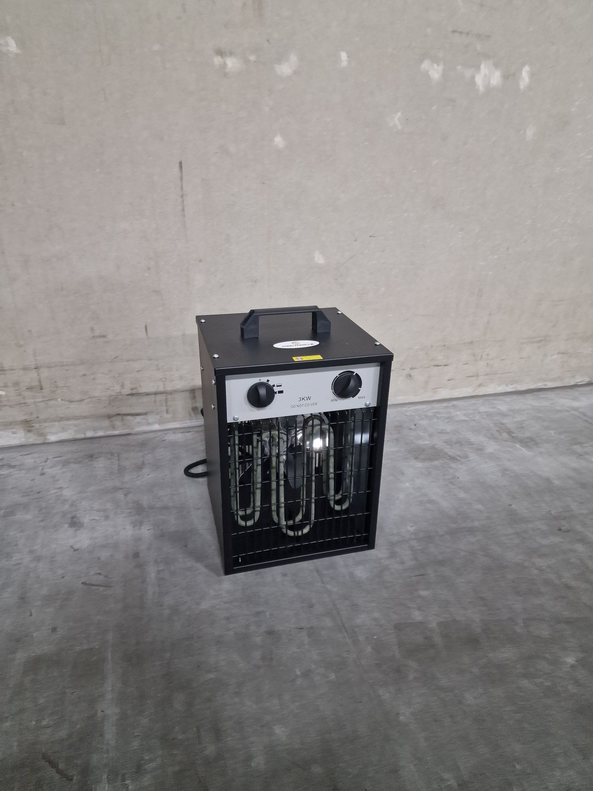 Een zwarte kachel staat op een betonnen vloer naast een muur.