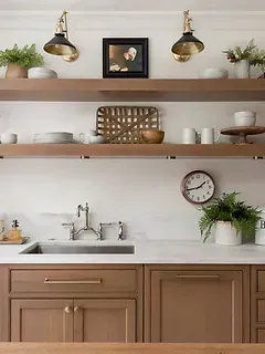 A kitchen with brown cabinets , a sink , and a clock on the wall.