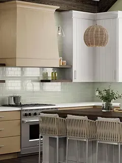 A kitchen with stainless steel appliances , wooden cabinets , a stove and a bar.