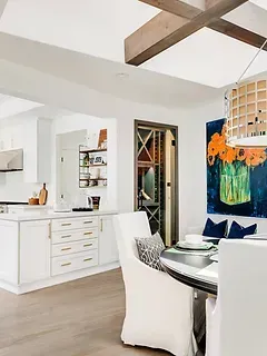 A kitchen and dining room with a table and chairs and a painting on the wall.