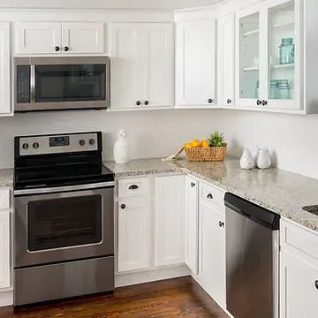 A kitchen with white cabinets , a stove , a microwave , and a dishwasher.