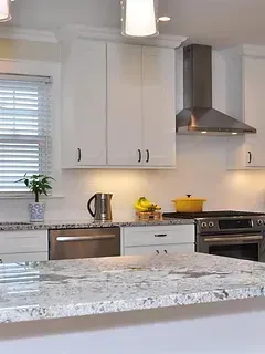 A kitchen with granite counter tops , stainless steel appliances , and white cabinets.