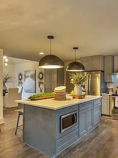 A kitchen with a large island in the middle and stainless steel appliances.