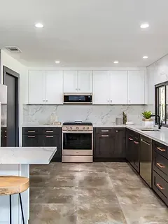 A kitchen with stainless steel appliances , marble counter tops , black cabinets and a stove.
