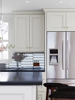 A kitchen with white cabinets and a stainless steel refrigerator.