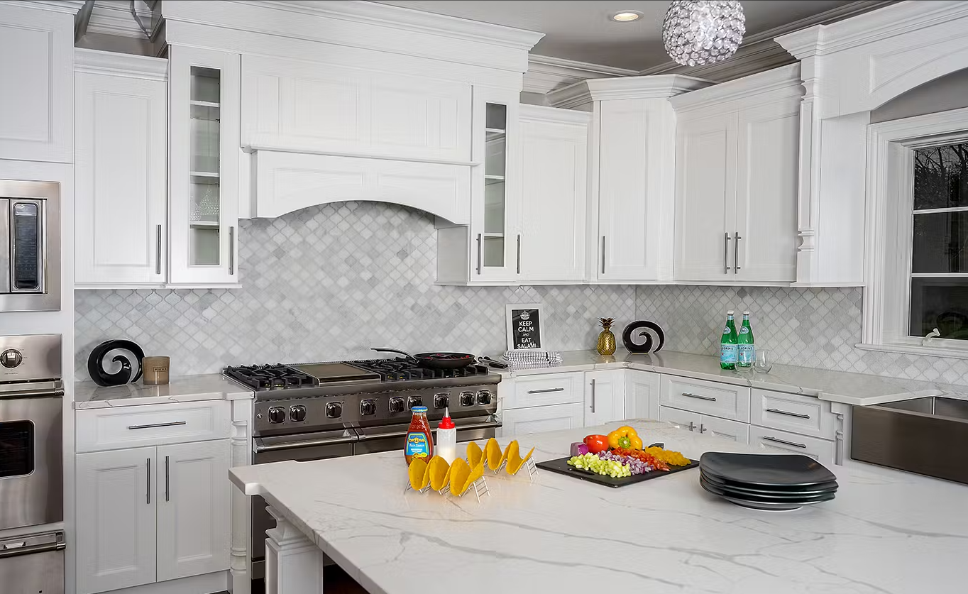 A kitchen with white cabinets , stainless steel appliances , and a large island.