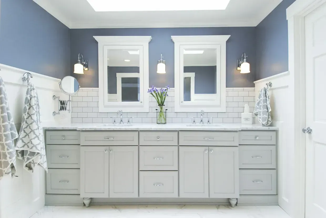 A bathroom with two sinks , two mirrors , and a skylight.
