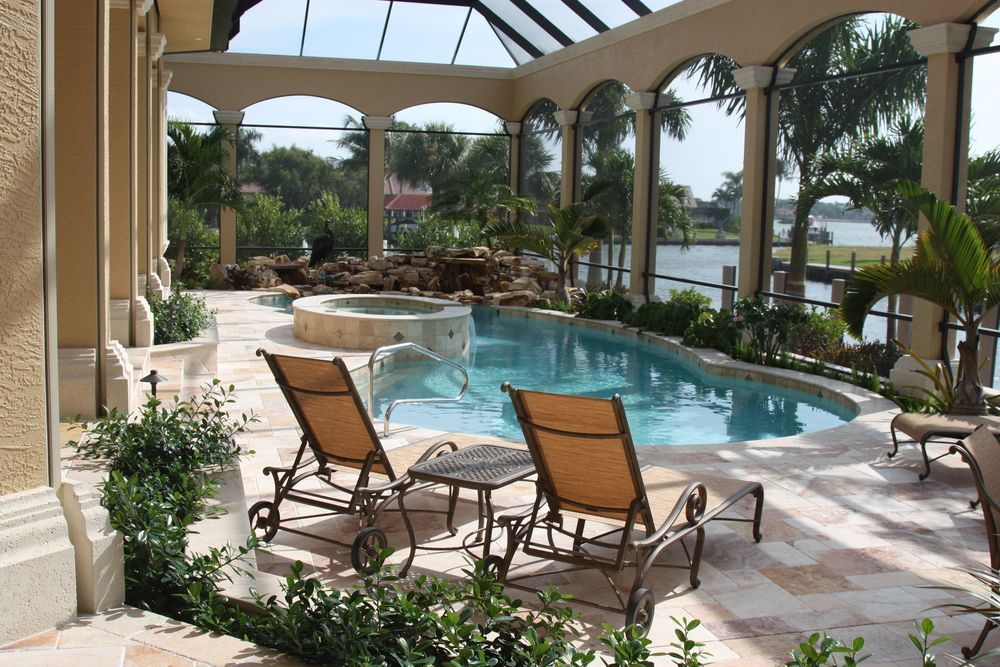 A large swimming pool is surrounded by chairs and a gazebo