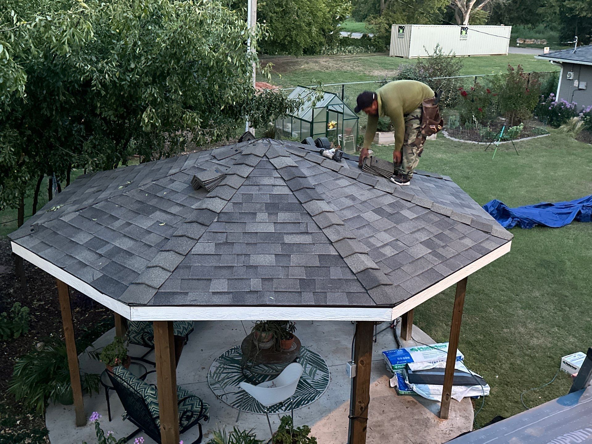 A man is working on the roof of a gazebo.
