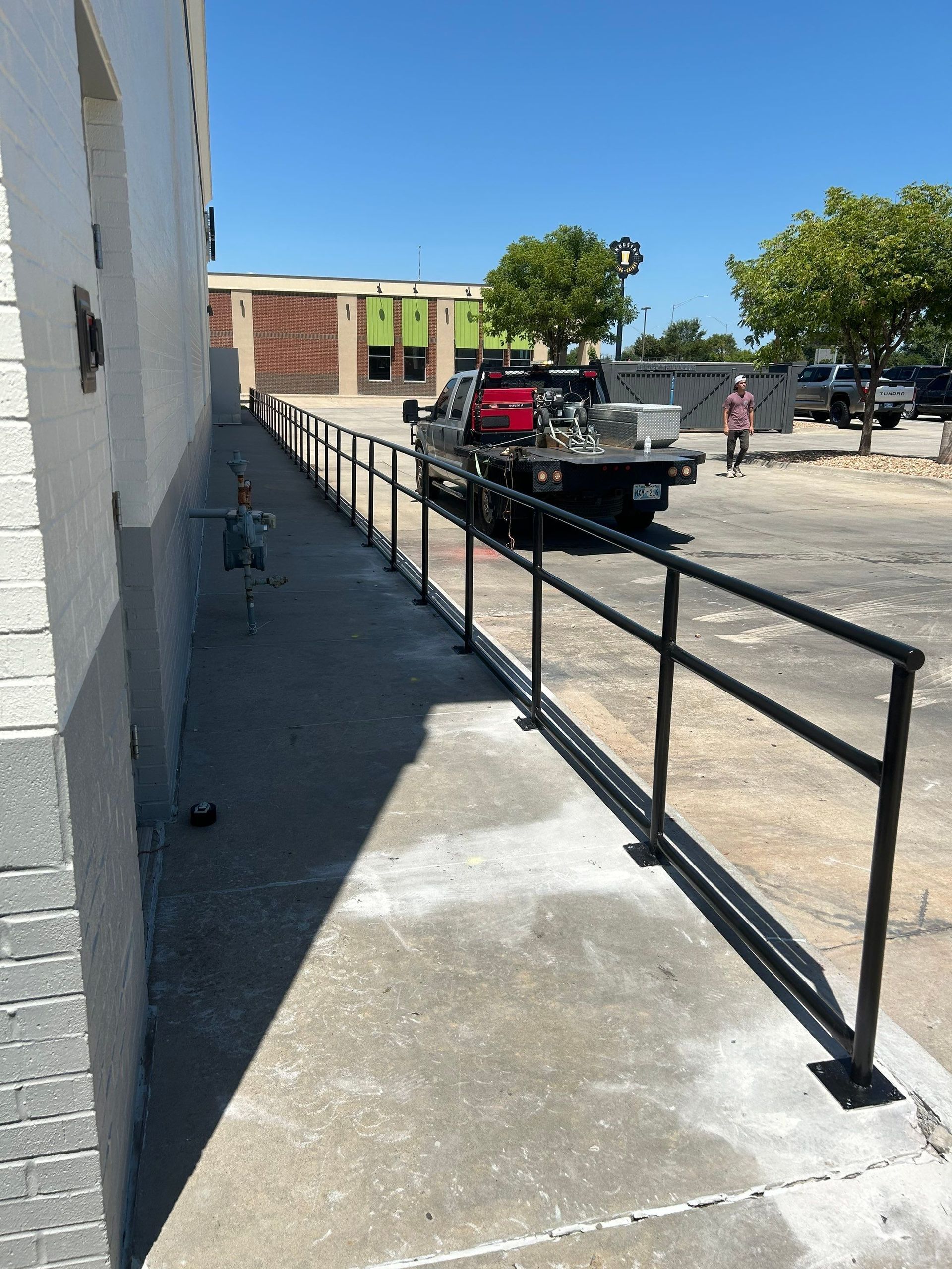 A tow truck is parked on the sidewalk next to a railing.