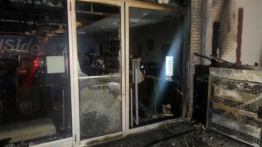 A building that has been damaged by a fire and has a broken glass door.