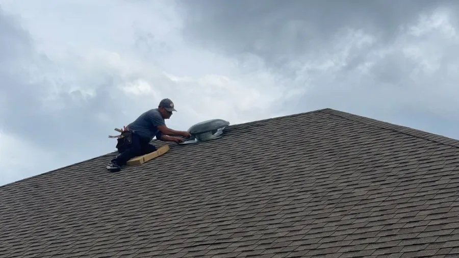 A man is working on the roof of a house.