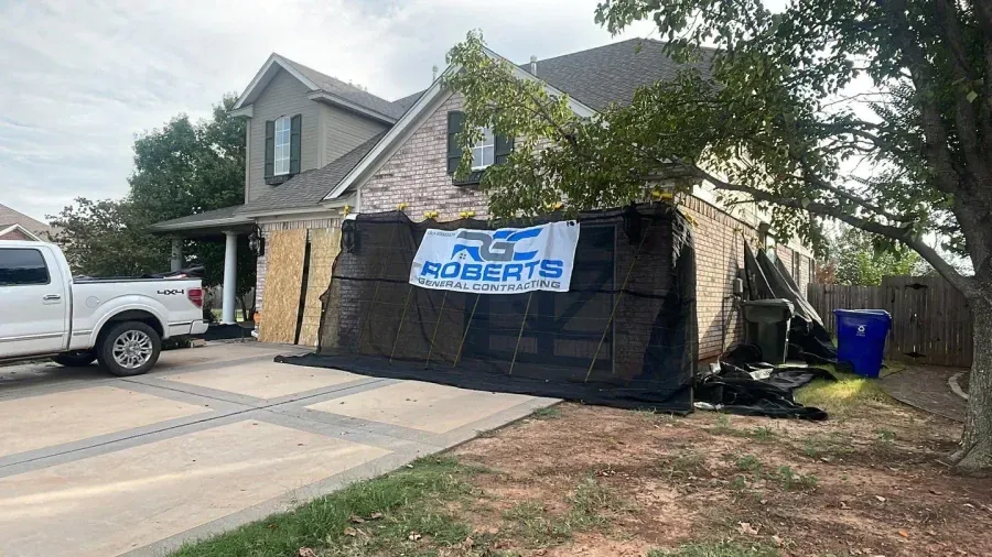 A white truck is parked in front of a house that has been damaged by a fire.