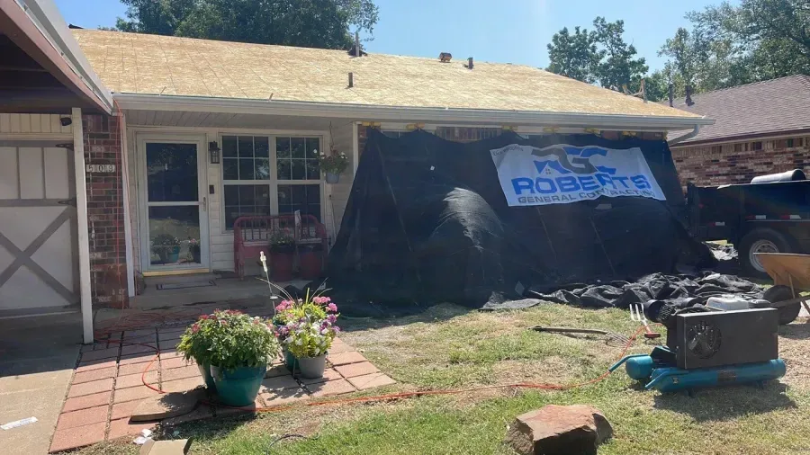 A house with a roof that is being repaired and a sign in front of it.