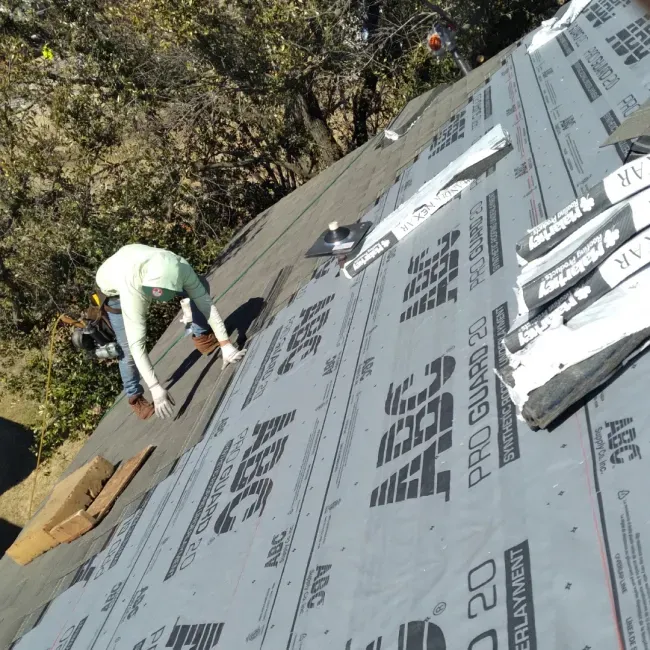 A person is working on a roof with abc pro guard