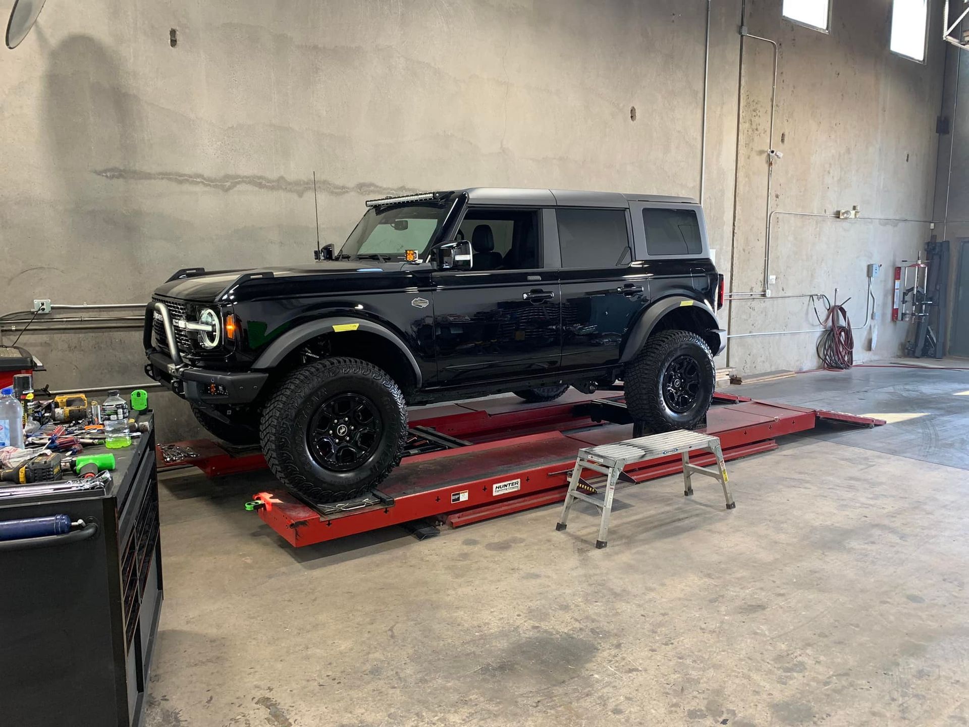 Black Ford Bronco SUV on a red car lift inside a garage.