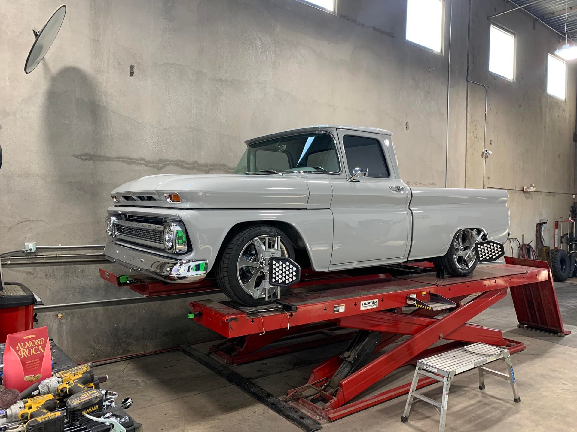 Gray classic pickup truck on a red lift in a garage, undergoing an alignment check.
