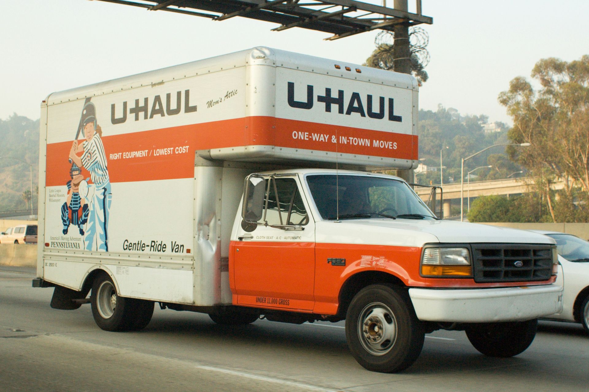 A U-Haul moving truck that's driving down a suburban road in Summerville, SC on a sunny summer day.