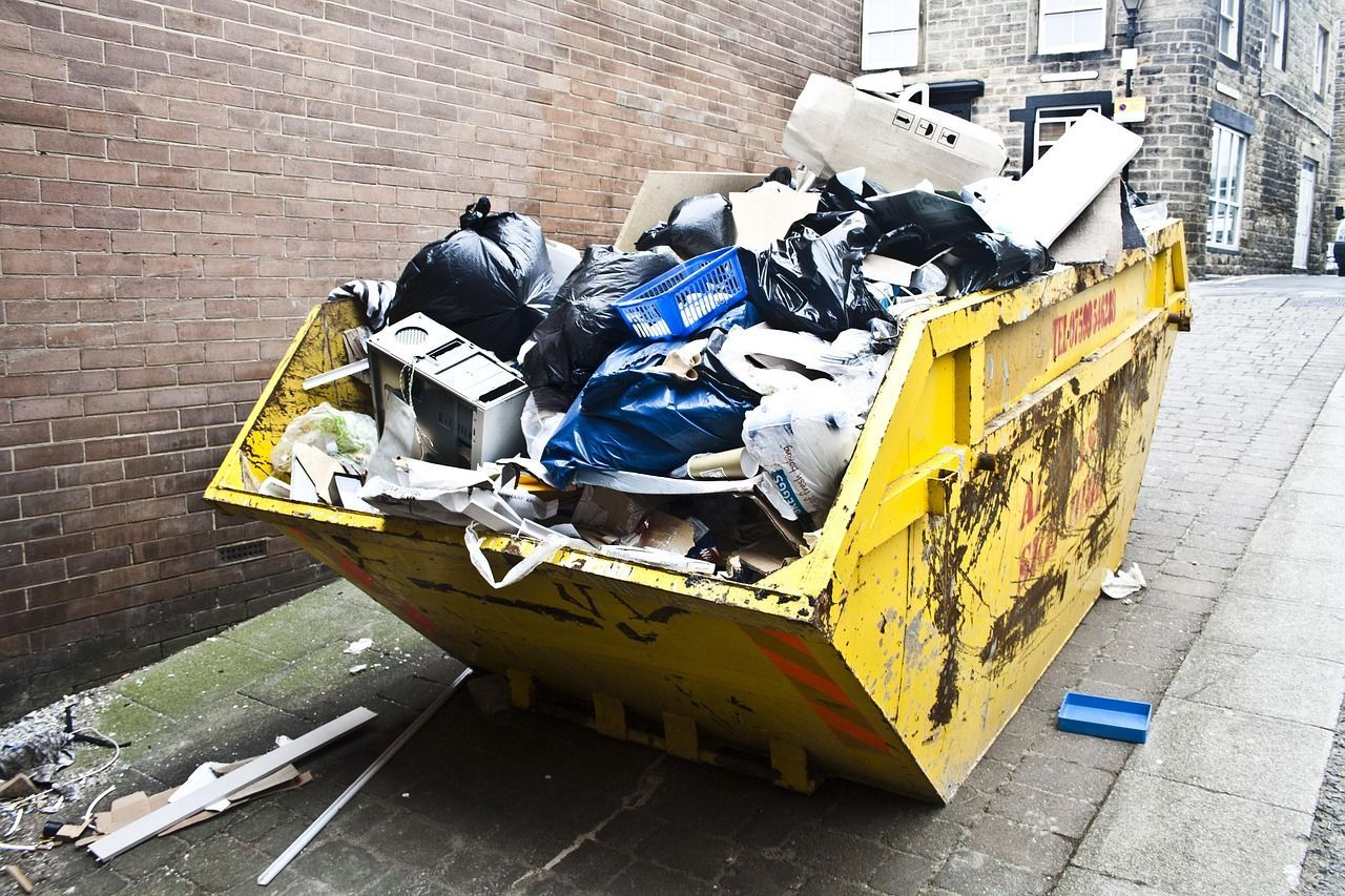 rubbish stacked on top of yellow skip bin