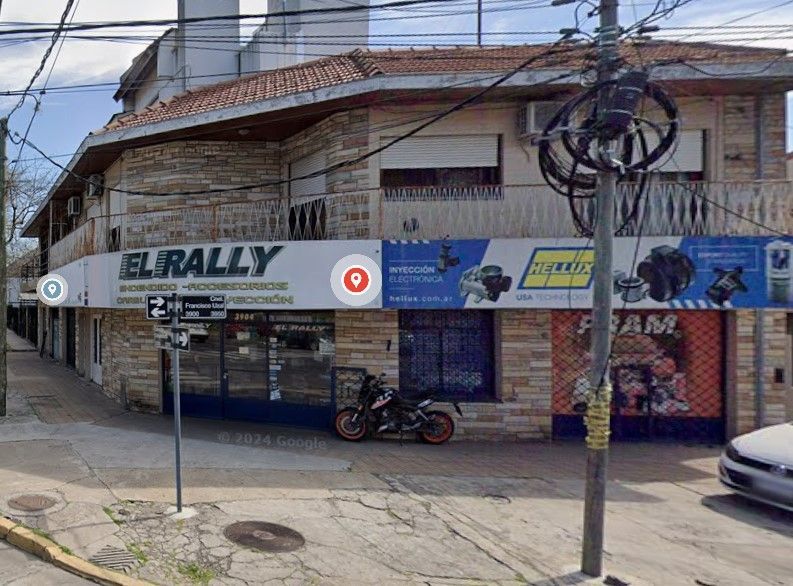Una motocicleta está estacionada frente a una tienda llamada el rally.