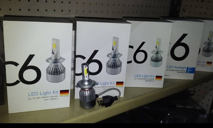 Varias cajas de faros LED C6 están alineadas en un estante.