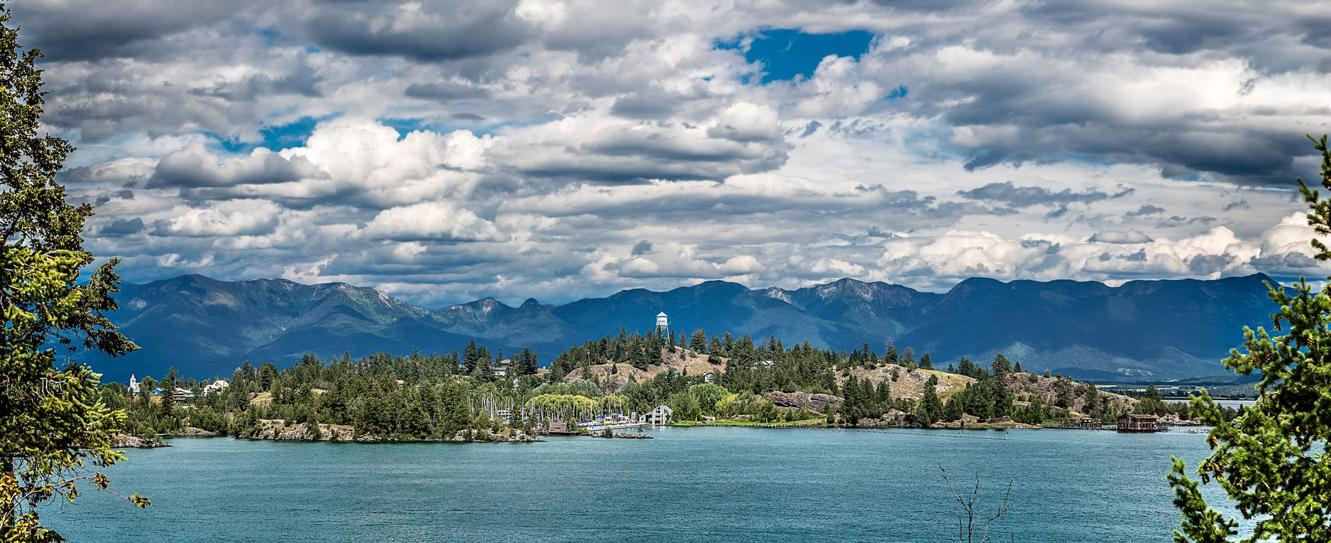 Lake with cloudy sky and mountains in the distance.