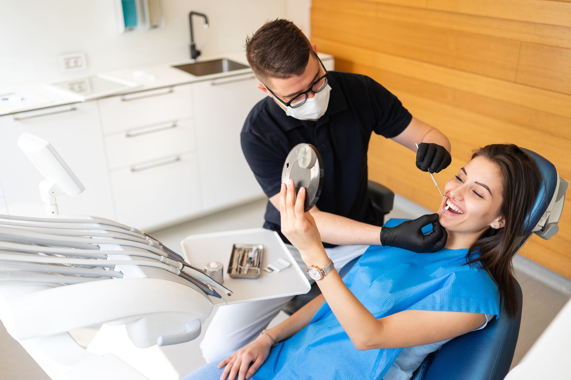 Una donna è seduta sulla poltrona del dentista mentre un dentista le esamina i denti.