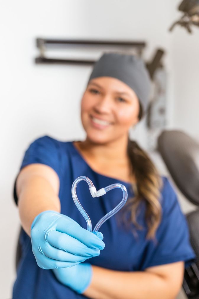 Una dentista tiene in mano un oggetto a forma di cuore.