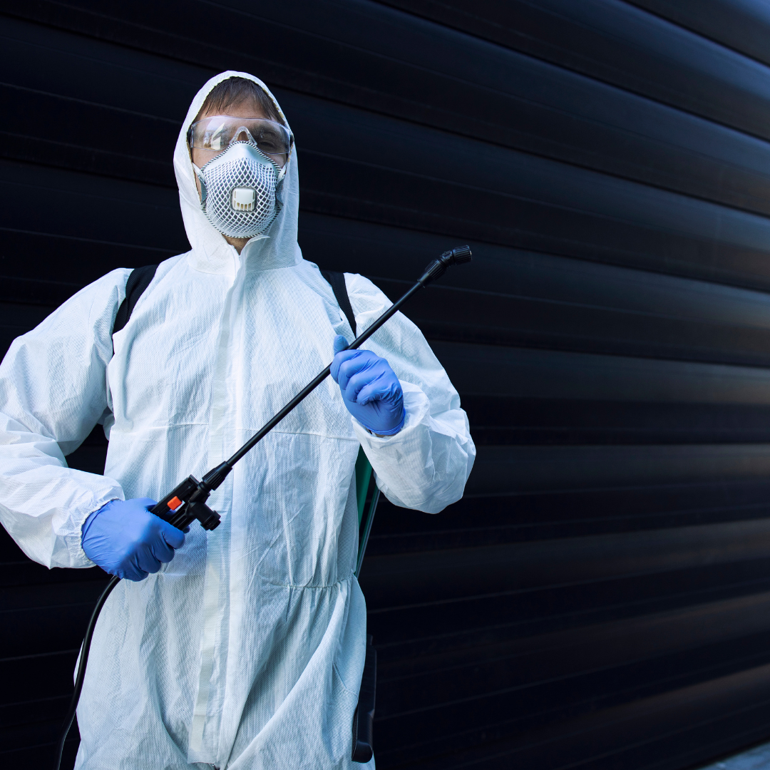 A man in a protective suit is spraying something with a sprayer.