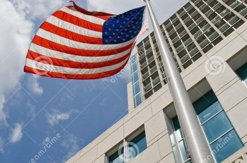 an american flag is flying in front of a tall building .