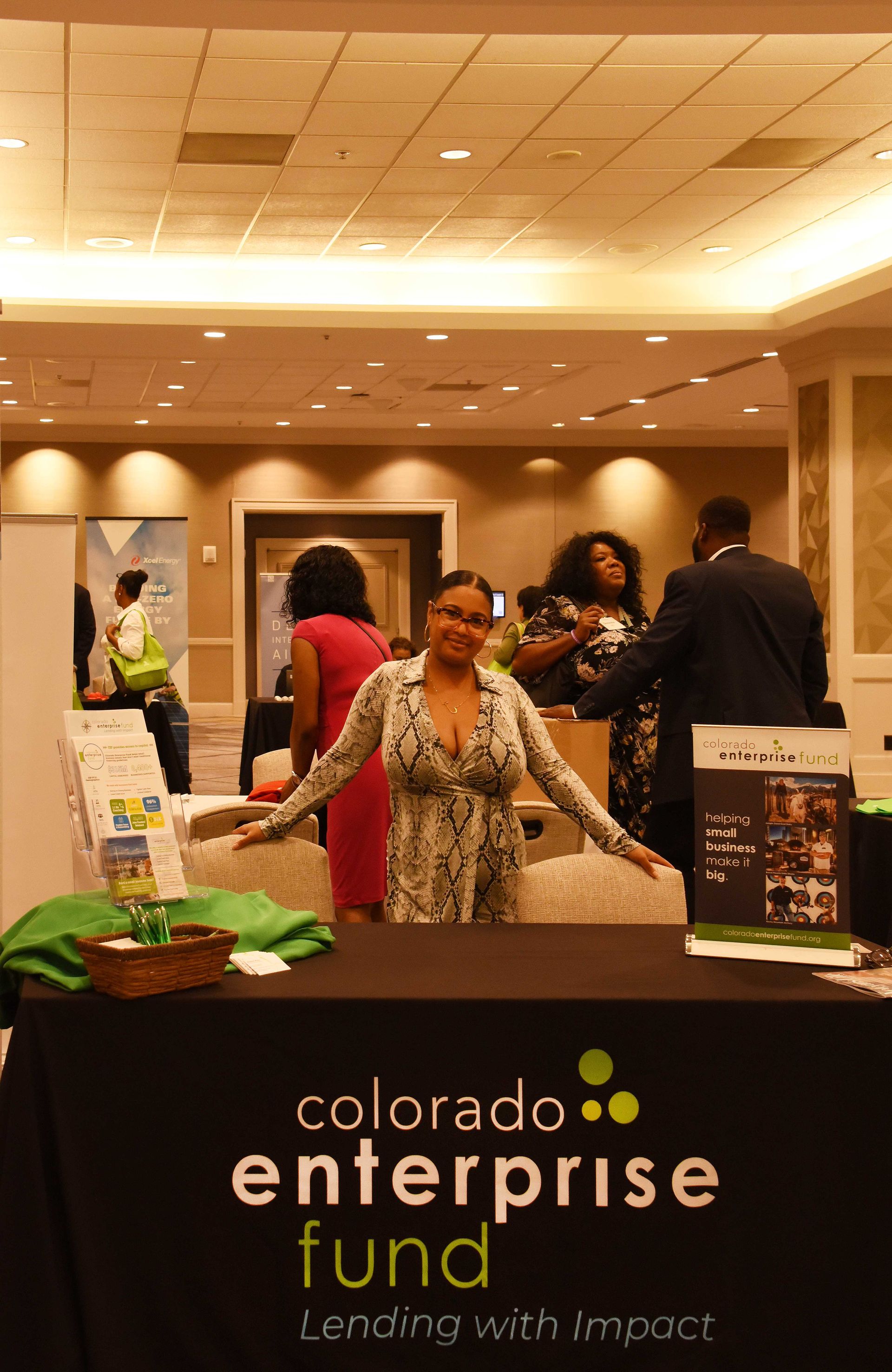 A woman stands in front of a table that says colorado enterprise fund