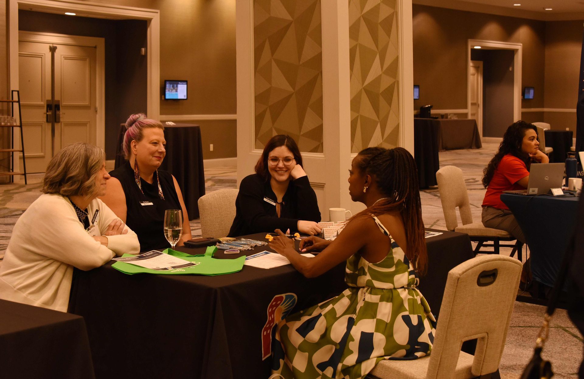 A group of women are sitting at a table talking to each other.