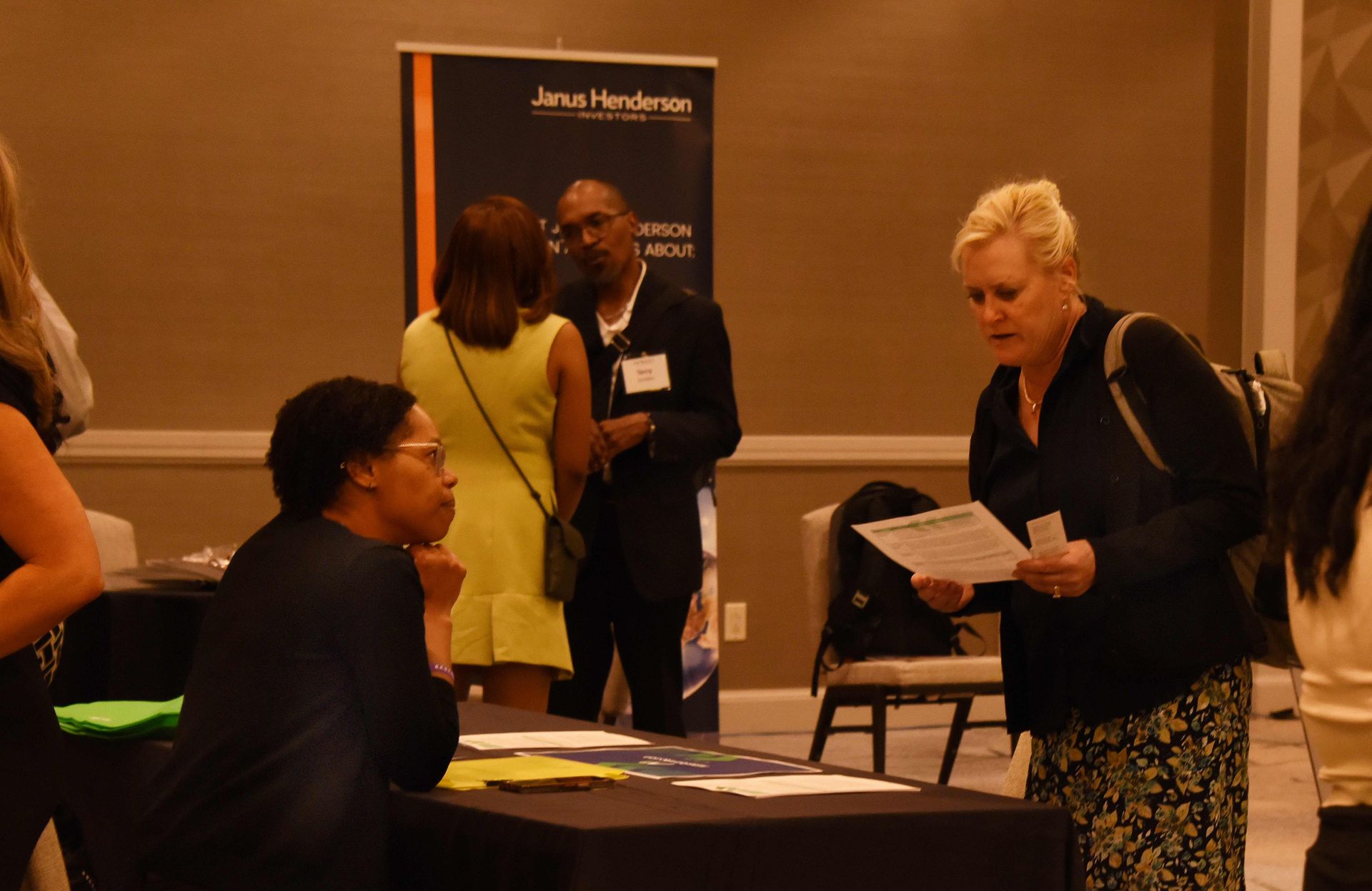 A group of people are standing around a table at a job fair.