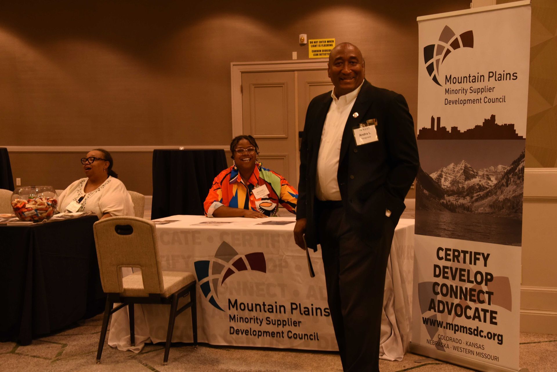 A man is standing in front of a table with a sign that says ' certify develop connect advocate '